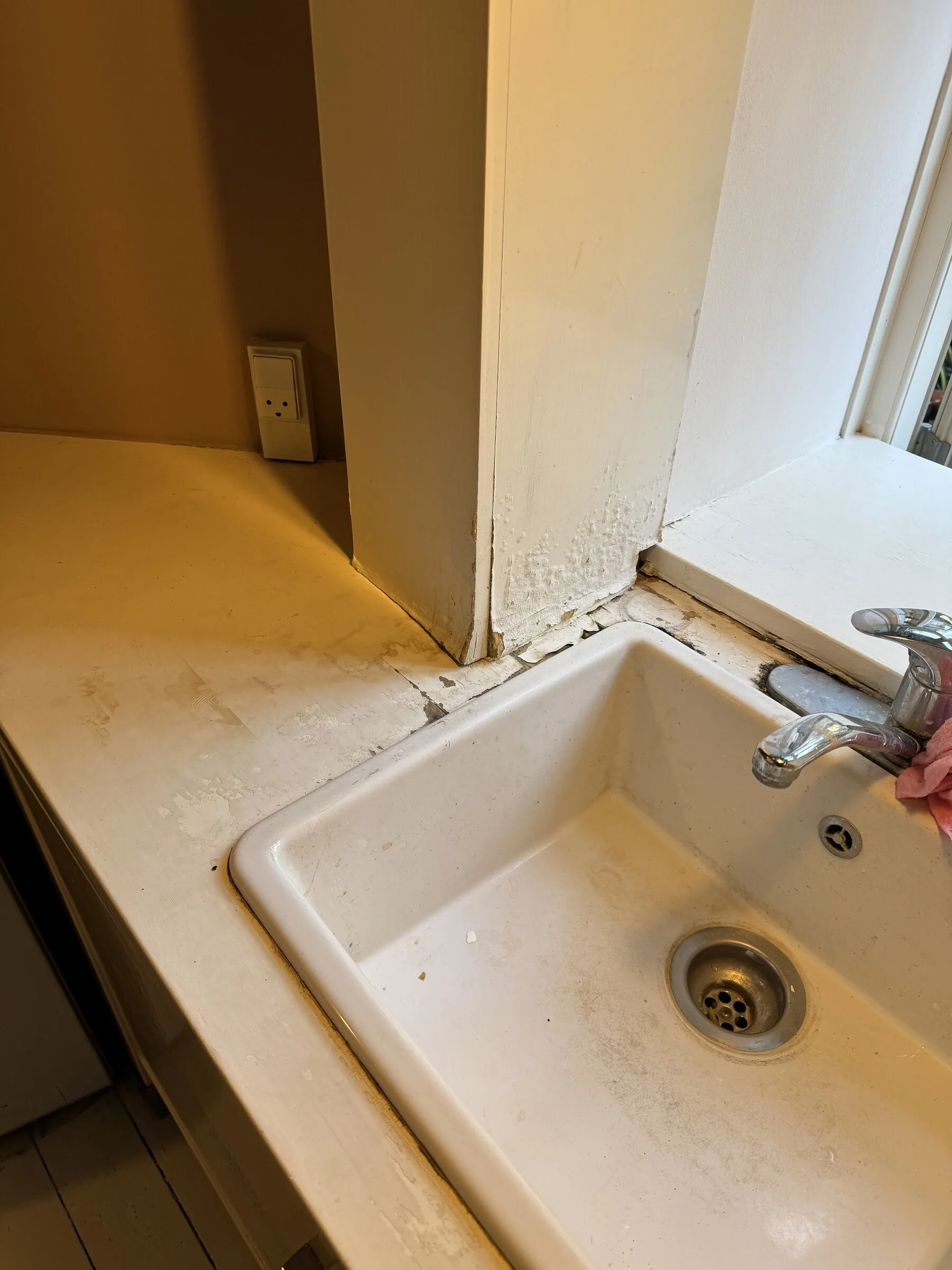 Old countertop before replacement, showing wear and staining around the sink edge