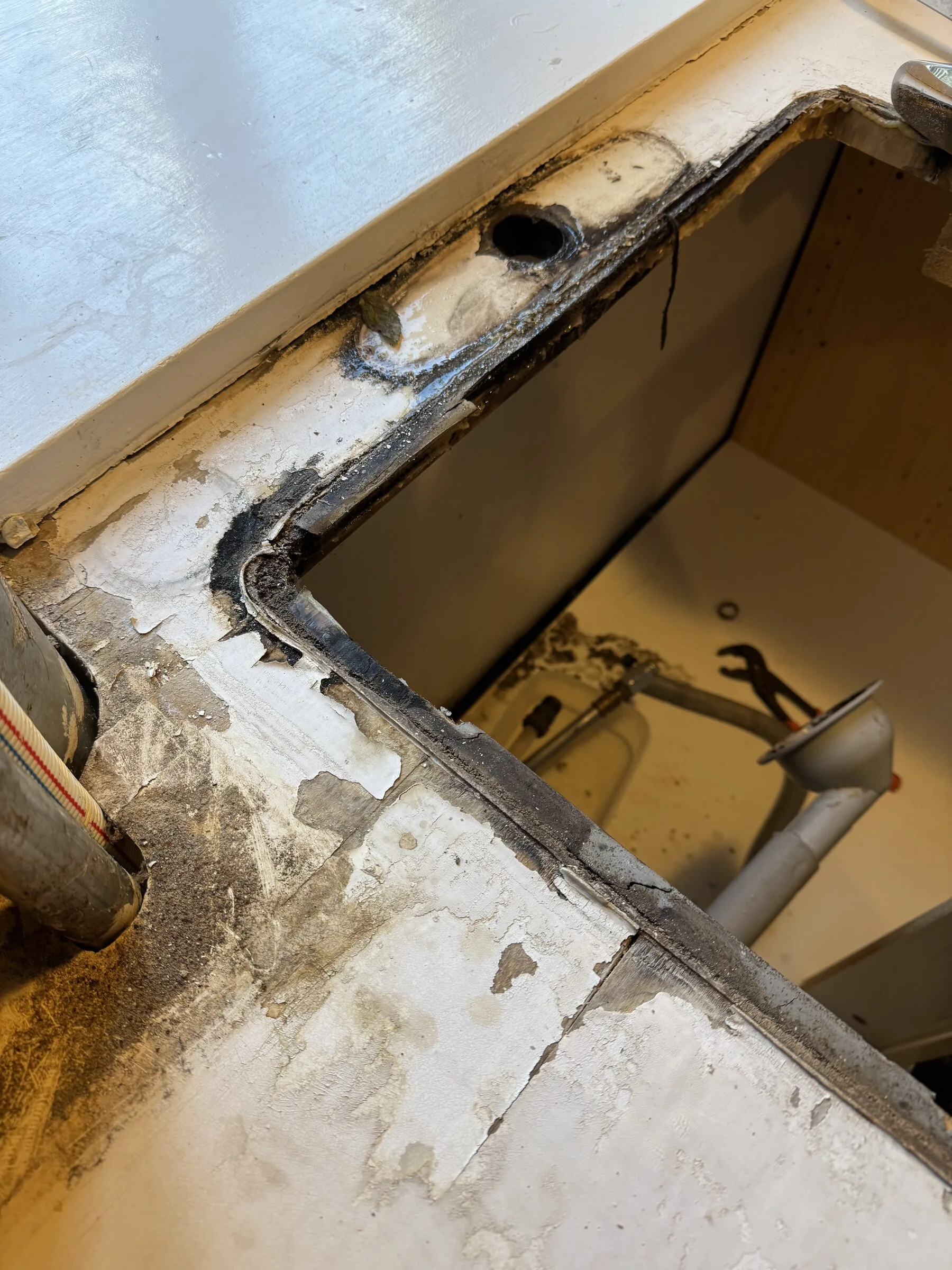 Close detail of the exposed sink opening and substrate during countertop replacement