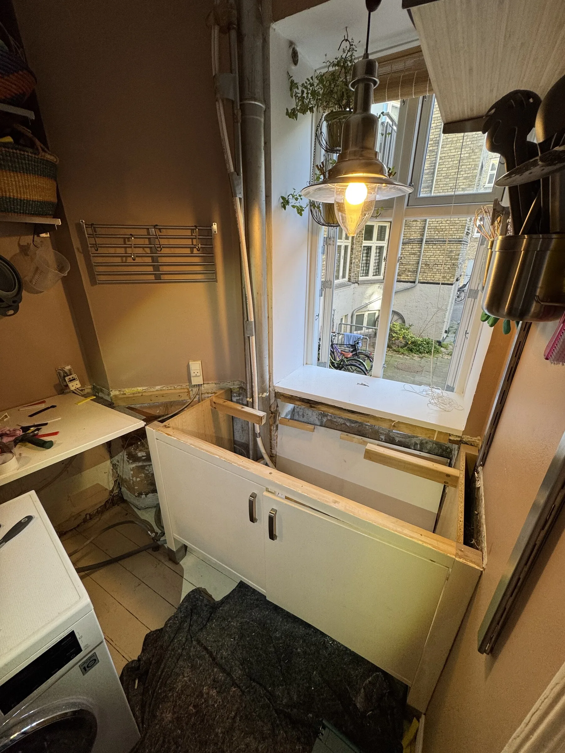 Kitchen during countertop removal, with the old top lifted away and the cabinet run exposed