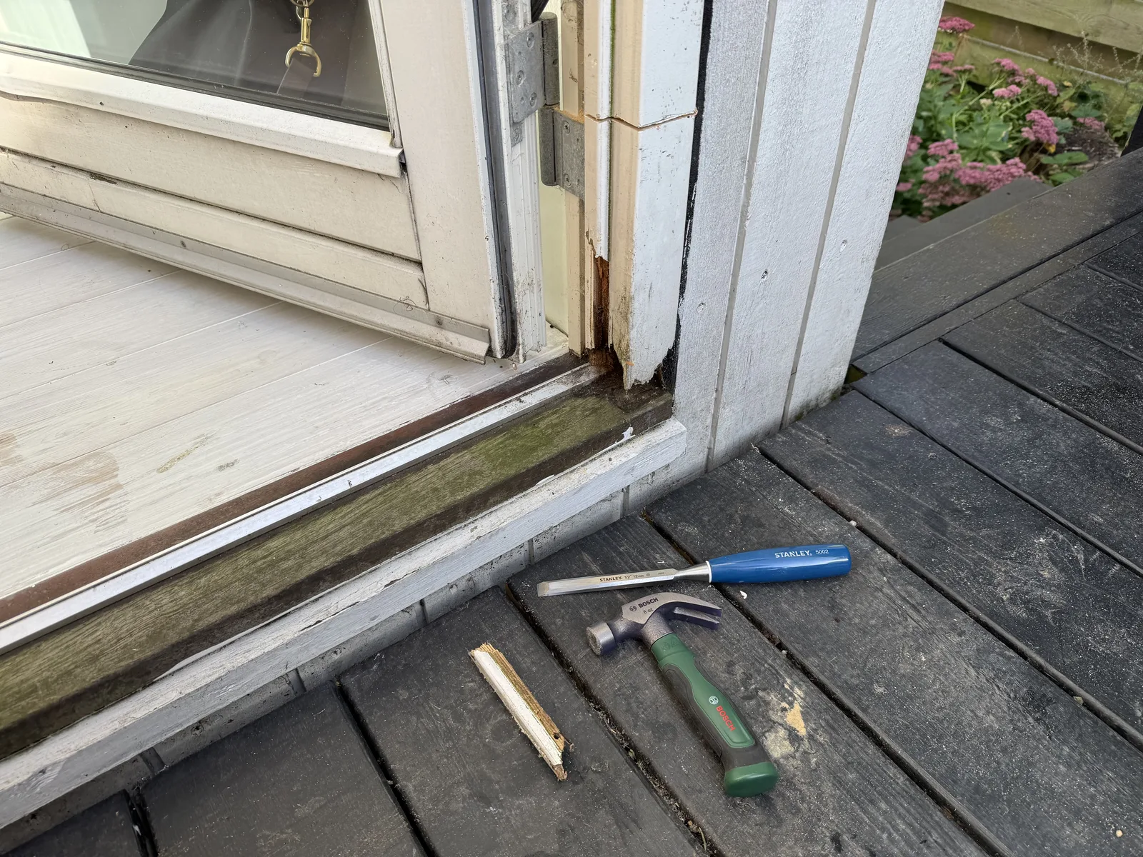 Rotten wooden base of exterior door frame before repair